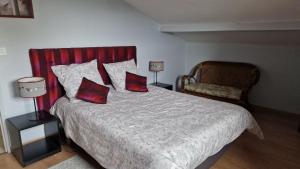 a bedroom with a bed with two red pillows and a chair at Gite La Baraque in Najac