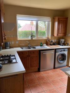 a kitchen with a sink and a washing machine at Cosy at Cumberland - Double room with shared bathroom in Dundonald