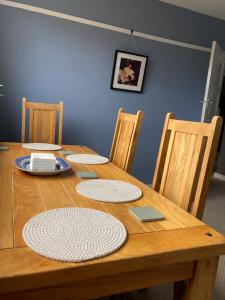 einem Holztisch mit vier Stühlen und einem Tisch mit Tellern darauf in der Unterkunft Cosy at Cumberland - Double room with shared bathroom in Dundonald
