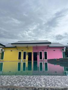 una casa colorata con acqua di fronte di D Sayang Homestay Parit Buntar MUSLIM SAHAJA a Parit Buntar