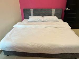 a bed with white sheets and a pink wall at D Sayang Homestay Parit Buntar MUSLIM SAHAJA in Parit Buntar +4 photos