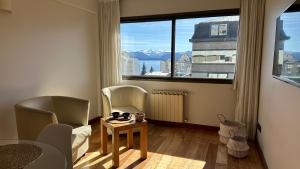 a living room with a table and chairs and a large window at Urban Patagonia Apart in San Carlos de Bariloche