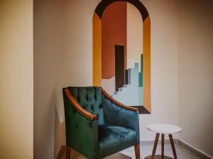 una sedia verde seduta in una stanza con un dipinto di Dervish Han Boutique Hotel a Istanbul