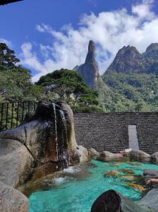einem Wasserfall in einem Pool mit Bergen im Hintergrund in der Unterkunft Casa 2 qtos, sendo suíte com cama Queen ar condicionado in Guapimirim