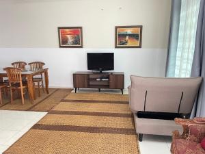 - un salon avec une télévision, une chaise et une table dans l'établissement Kuza Homes Batu Berendam, à Malacca