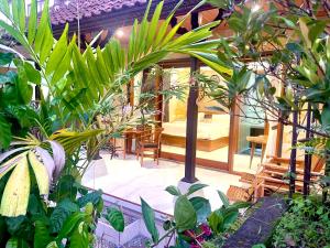 un jardín con plantas y una habitación con sofá en Ayu Homestay, en Ubud