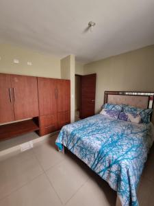 a bedroom with a bed with a blue comforter and wooden cabinets at Ferienhaus La Romana in La Romana