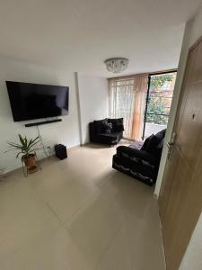 a living room with a couch and a flat screen tv at Habitacion Con Balcon Privado in Sabaneta