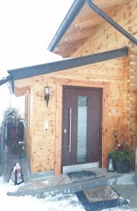 瓦格賴恩的住宿－Chalet Bergheimat，小木屋,雪中设有黑色门