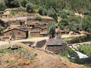 a group of buildings on a hill next to a river at Casa dos Veados in Ladeiras