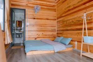 a bed in a room with a wooden wall at K'Ho Cil Homestay Tà Nung in Da Lat