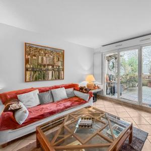 ブローニュ・ビヤンクールにあるCharmant Appartement au Cœur de Boulogneの赤いソファとガラスのテーブルのあるリビングルーム