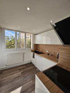 una cucina con armadi bianchi e una grande finestra di Charmant & spacieux 3 chambres - MM Apartment - Lyon Grand Parilly a Vénissieux