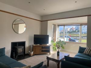 a living room with a couch and a television at Harbour Views 3 Bed Townhouse with private off street parking and office in Portstewart