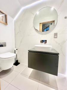 a white bathroom with a sink and a mirror at Stylish 2BR Designer Flat Holland Park in London