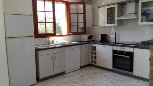 eine Küche mit weißen Schränken, einem Waschbecken und einem Fenster in der Unterkunft Grands appartement à Ciboure in Ciboure