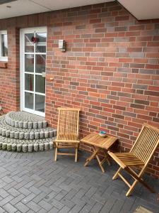 two chairs and a table in front of a brick wall at Lütte Stuv in Kollmar