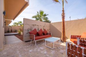 eine Terrasse mit einem Sofa, einem Tisch und Palmen in der Unterkunft Villa Saadia in Douar Bellouk