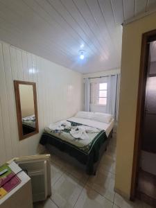 a bedroom with a bed in a room with a mirror at Pousada Miniférico in Campos do Jordão