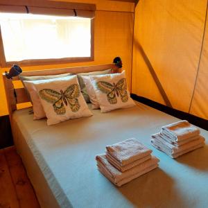 1 cama con toallas, almohadas de mariposa y ventana en Glamping Vive Tus Suenos -Libertad- Caminito del Rey en Alora