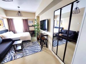 un soggiorno con letto e specchio di Cozy Studio Unit, Avida Towers Aspira a Cagayan de Oro