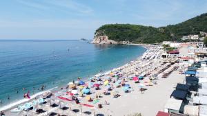 a group of people on a beach with umbrellas at Tiny House Montenegro in Petrovac na Moru