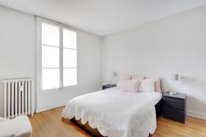 a white bedroom with a bed and a window at UNESCO-SUFFREN in Paris