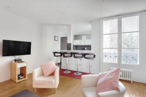 uma sala de estar com um sofá e cadeiras e uma televisão em UNESCO-SUFFREN em Paris