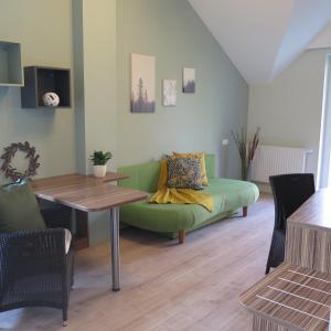 ein Wohnzimmer mit einem grünen Sofa und einem Tisch in der Unterkunft Rosenhotel - Serviced Apartments in Zwentendorf