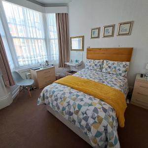 a bedroom with a bed and a desk and windows at Ainsley Court Guest House in Scarborough