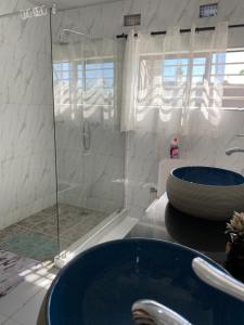 La salle de bains est pourvue d'une douche et de 2 lavabos bleus. dans l'établissement Swiss Luxury Apartments, à Ndola