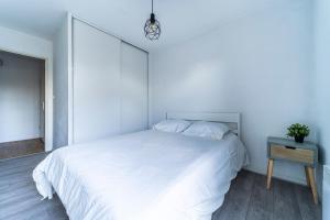 a white bedroom with a white bed and a night stand at T2 avec Terrasse Citadelle in Lille