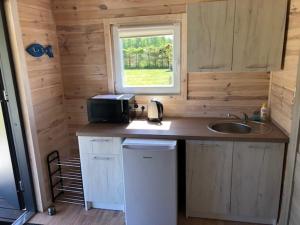 eine kleine Küche mit einem Waschbecken und einem Fenster in der Unterkunft Camp-Classic in Smołdziński Las