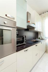 a white kitchen with white cabinets and a microwave at TWO SPACIOUS BEDROOMS 1 MINUTE TO METRO STOP in Milan
