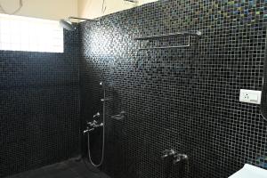 baño de azulejos negros con ducha y lavamanos en Athithi Resorts, en Yelagiri