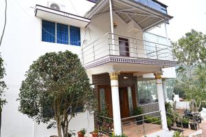 Casa blanca con balcón y árbol en Athithi Resorts, en Yelagiri
