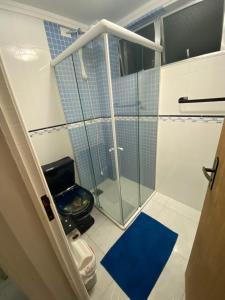 uma casa de banho com uma cabina de duche em vidro e um WC. em Apartamento enseada Guarujá no Guarujá