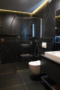 a black bathroom with a toilet and a sink at Apartament Koha 