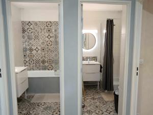ein Badezimmer mit einer Badewanne, einem Waschbecken und einem Spiegel in der Unterkunft MAISON 4 CHAMBRES AVEC JARDIN in Dampierre-en-Burly