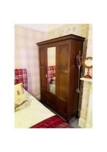 um quarto com um armário de madeira ao lado de uma cama em The Old Merchants House - The Highlands Room em Southampton