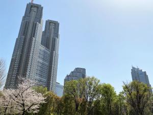two tall buildings in a city withakuraakura trees at APA Hotel & Resort Nishishinjuku-Gochome-Eki Tower in Tokyo