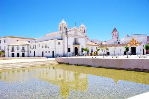 a church with a reflection in a pond in front of it at Praia da Luz Monique Apartment in Luz