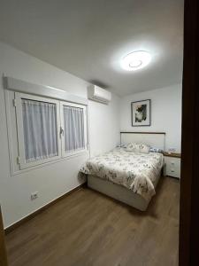 a white bedroom with a bed and a window at El Coso in Santa Cruz de la Zarza