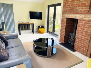 uma sala de estar com um sofá e uma mesa em frente a uma lareira em Romantic cottage for 2 with hot tub em Wimborne Minster