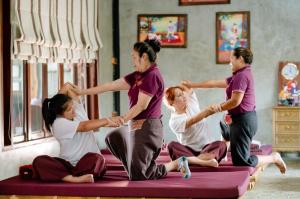 un gruppo di persone sedute su un letto a fare yoga di Srichaiyapura Wellness Resort a Ban Tha Phaniat