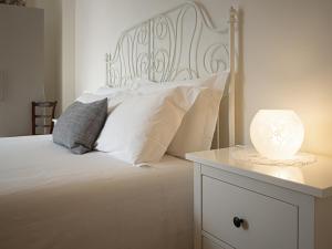 un letto con cuscini bianchi e una lampada su un comodino di Raviola e Tajarin a Verduno
