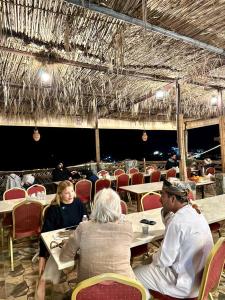 Guest house baldsayt في Bilād Sayt: مجموعة من الناس يجلسون على الطاولات في المطعم