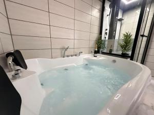 a bathroom with a bath tub with a sink at E Servagnat T3 luxe avec Sauna Jacuzzi et Hammam in Épernay