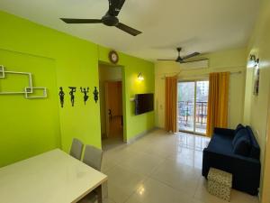 - un salon avec des murs verts, une table et un canapé dans l'établissement Merlin Legacy, à Kolkata