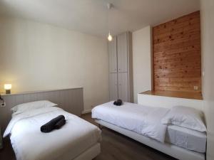 2 camas en un dormitorio con paredes blancas y suelo de madera en La perle de Ré au cœur de Saint Martin, en Saint-Martin-de-Ré